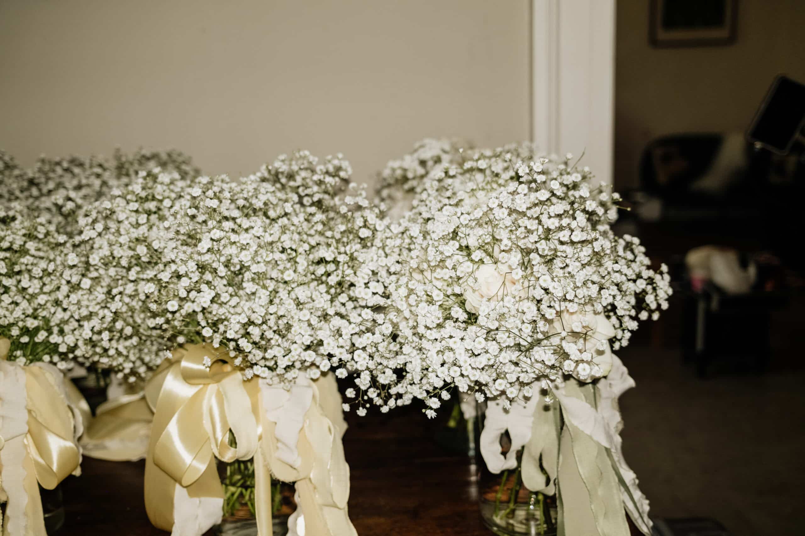 Bouquets de mariée avec gypsophile et roses délicates dans des vases en verre. Rubans satinés jaunes, crème et verts. Préparatifs.