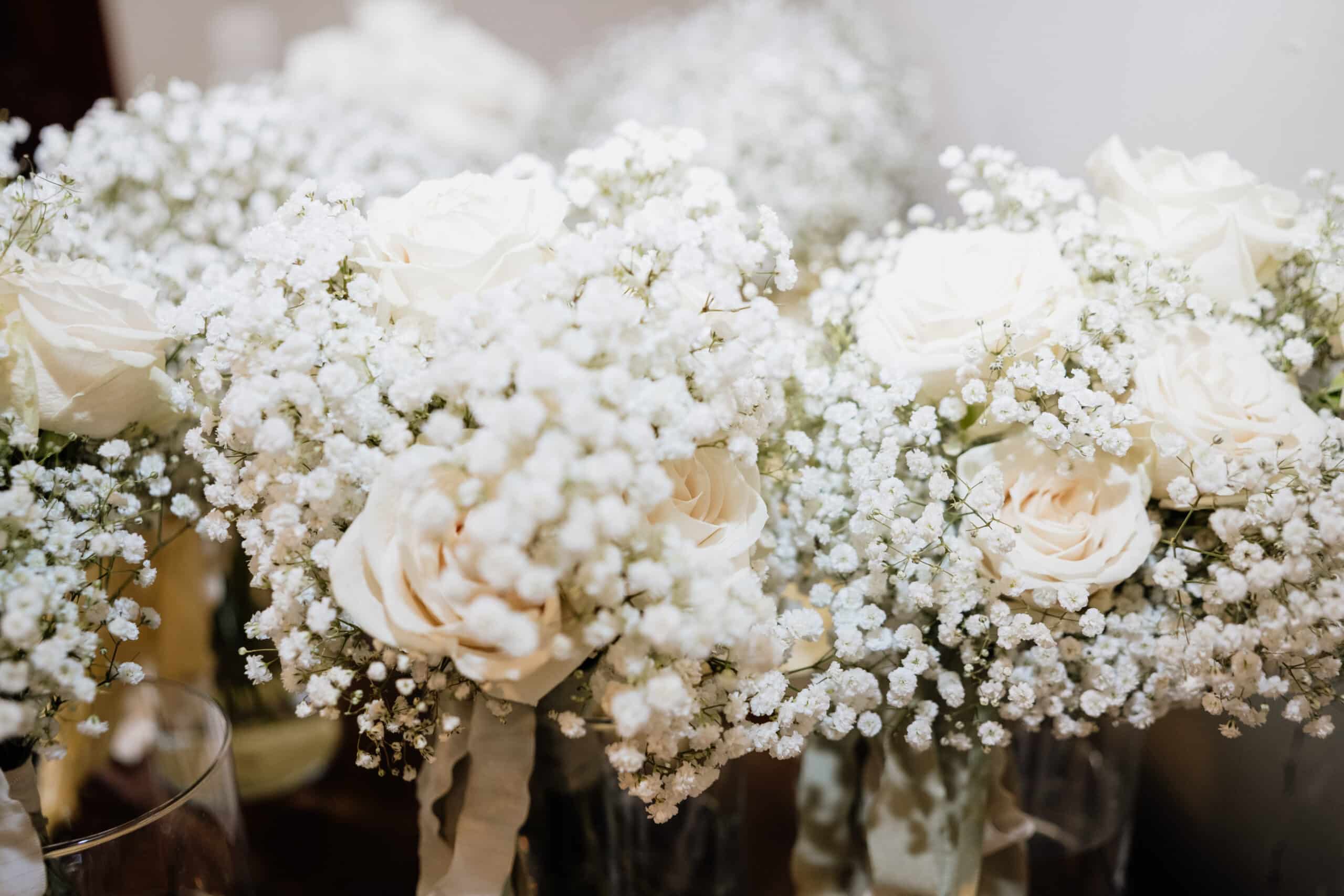 Bouquets de roses blanches et de gypsophile luxuriante en gros plan. Décoration florale romantique pour mariage dans des vases en verre.