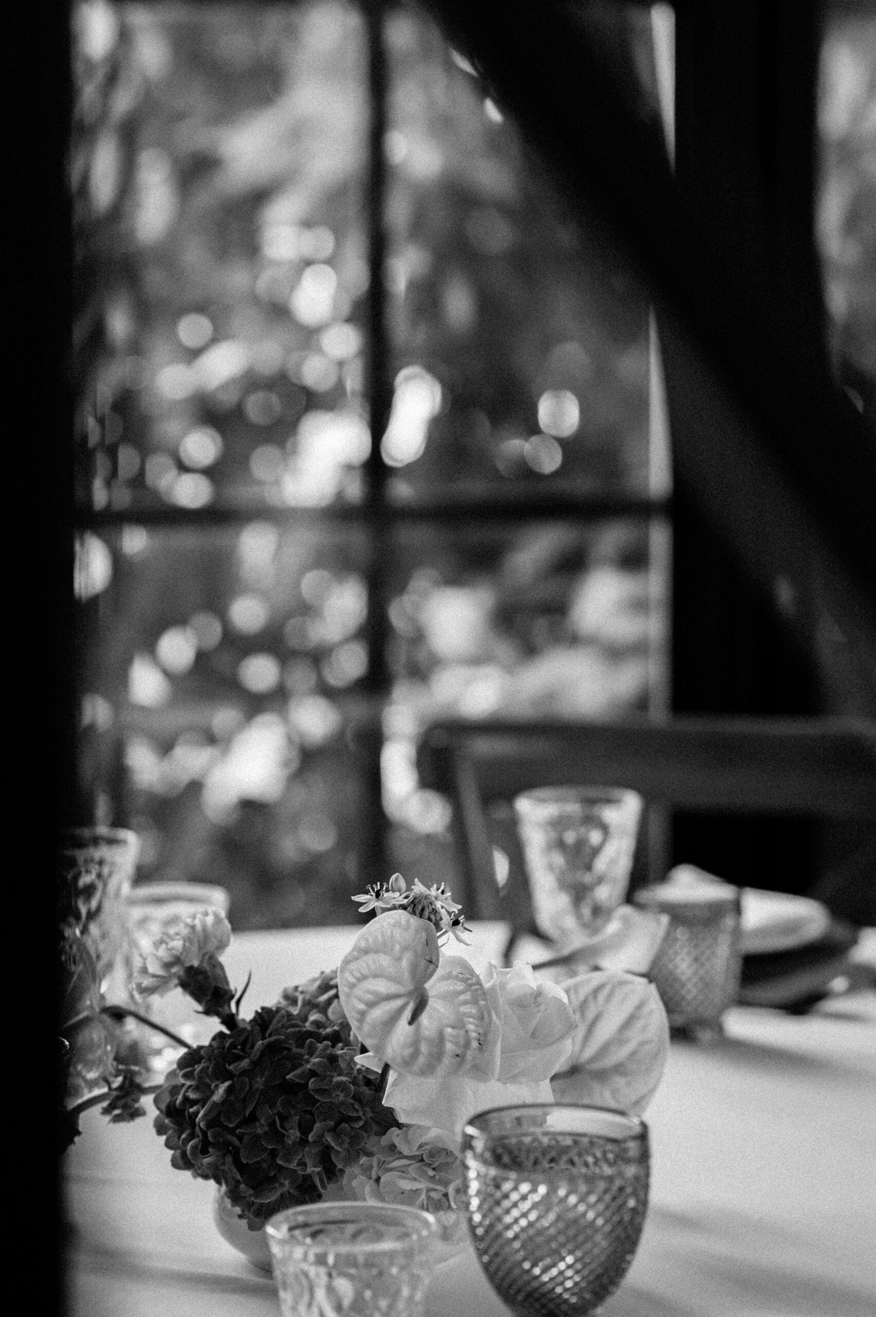 Élégante table de réception en noir et blanc. Centre de table composé d'Anthurium et d'Hortensia, entouré de verres texturés près de la fenêtre.